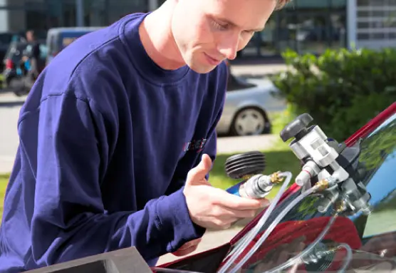 A person is using tools to repair the windshield of the car.