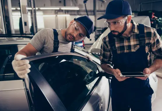 A group of men wearing goggles is inspecting the car's window glass.